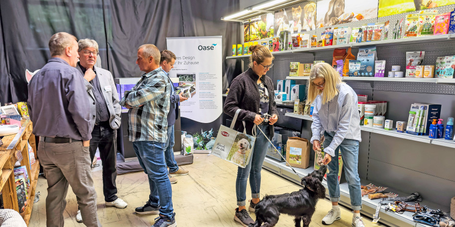 Petra Merkert von Flamingo  Pet Products zeigt Eva Sommer  von Zookauf Rheine im Raum  „Product Showcases“die Marty-Produktreihe, mit der sie Straßenhunden unterstützen.